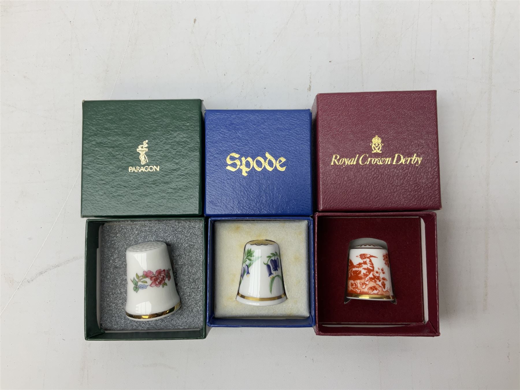 Quantity of thimbles to include twelve Irish Dresden lace examples, Royal Crown Derby, Spode, Portmeirion, Wedgwood, Royal Grafton etc, together with three display cases, many with certificates