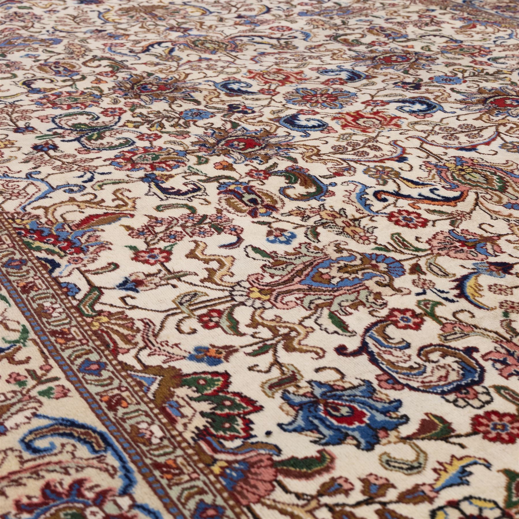 North West Persian Tabriz, hand-knotted carpet, ivory ground with dense scrolling vine-work, palmettes, flowering sprays, and stylized leaves framed by a principal border of scrolling floral motifs and palmettes and flanked by narrow guard borders, with cotton fringe ends