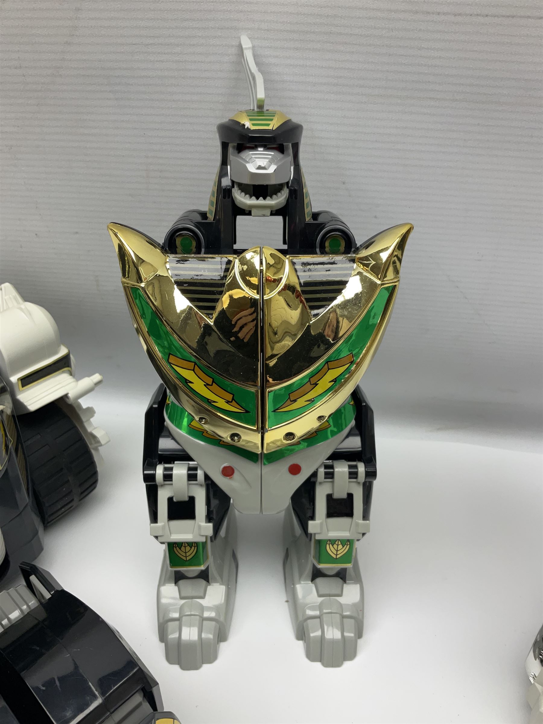 Collection of early 90s Mighty Morphin’ Power Rangers Zords, figures and accessories. Titanus the Carrier Zord, marked Bandai 1991; Green Dragonzord, incomplete; 1994 White Tigerzord with original instruction manual; 1993 Triceratops Dinozord, Mastodon Dinozord and Sabertooth Tiger Dinozord, Pterodactyl Dinozord, missing guns; with 1993 Power Morpher and original Power Coins, with further related figures, accessories and weapons