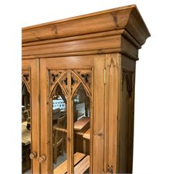 Ecclesiastical Gothic design waxed pine dresser, projecting cornice over four glazed doors, pierced and carved tracery work, moulded rectangular top over four drawers and four cupboards, the doors with Gothic design arched panels carved with flower heads and foliage, on plinth base