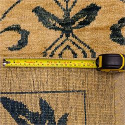 Late 20th century Turkish hand-woven carpet, golden beige field decorated with a repeating lattice of stylized medallions enclosing boteh and angular foliate motifs linked by issuing scrolling vinery within a border of complementary stylized leaf scrolls
