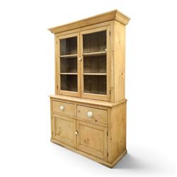 Victorian stripped pine and glazed dresser, projecting ovolo cornice over glazed doors enclosing two shelves, the base fitted with two drawers over panelled cupboards with ceramic handles, on moulded skirted base