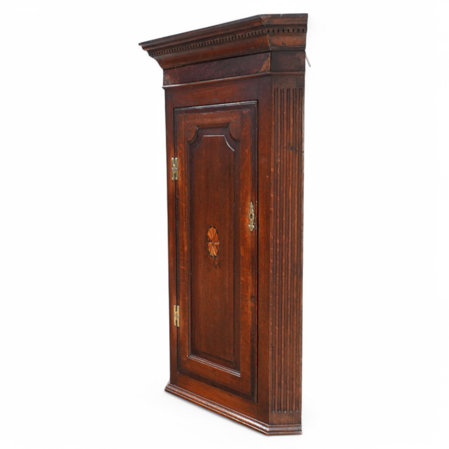 19th century mahogany corner wall cupboard, with projecting cornice and dentil moulding above a single door with shaped fielded panel and satinwood fan inlay, flanked by fluted pilasters, fitted with shaped interior shelving