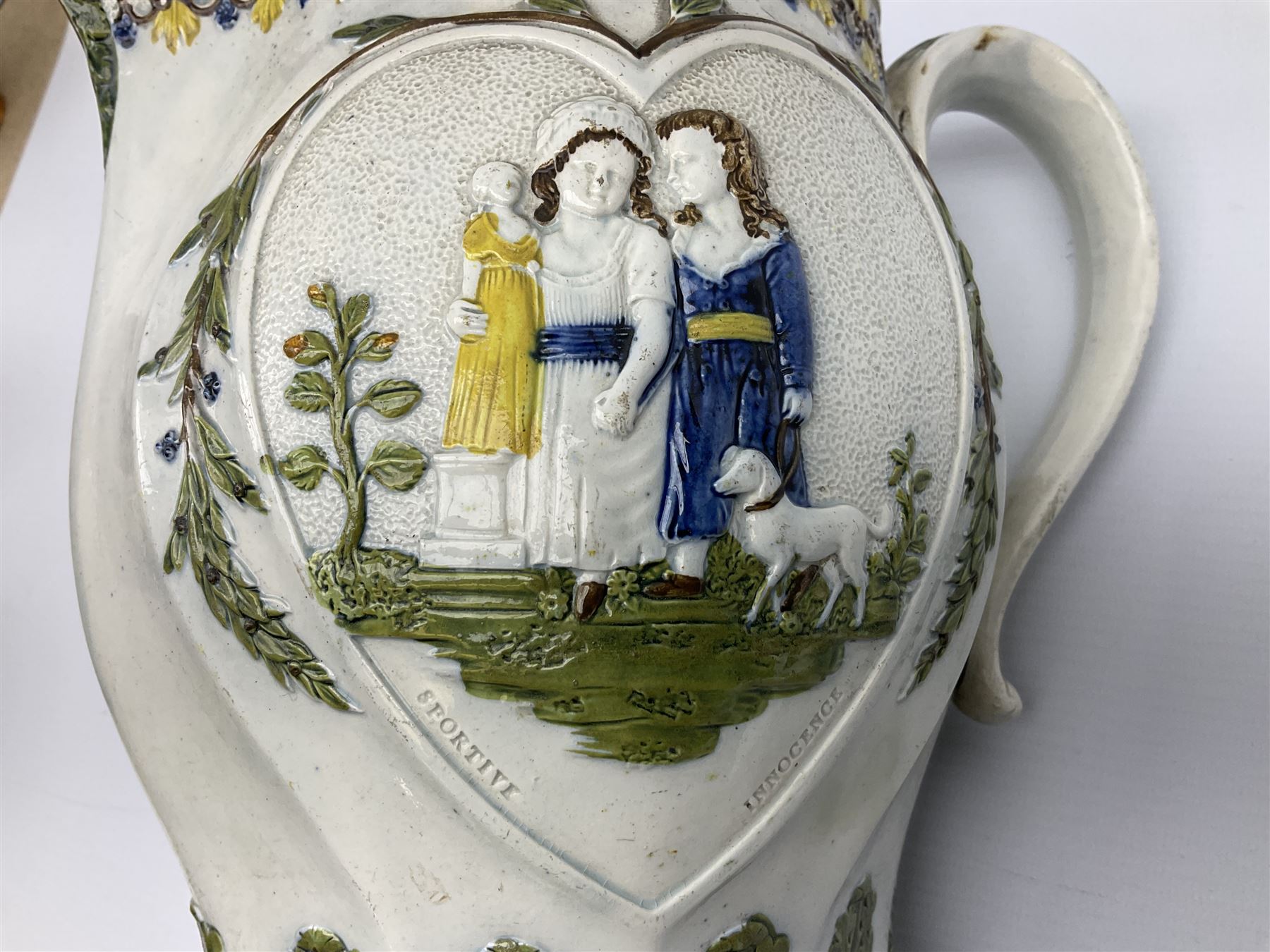 Early 19th century Prattware jug, circa 1800, decorated with two heart shaped panels of children, titled Sportive Innocence and Mischievous Sport, further decorated with acanthus and foliate borders, H22cm
