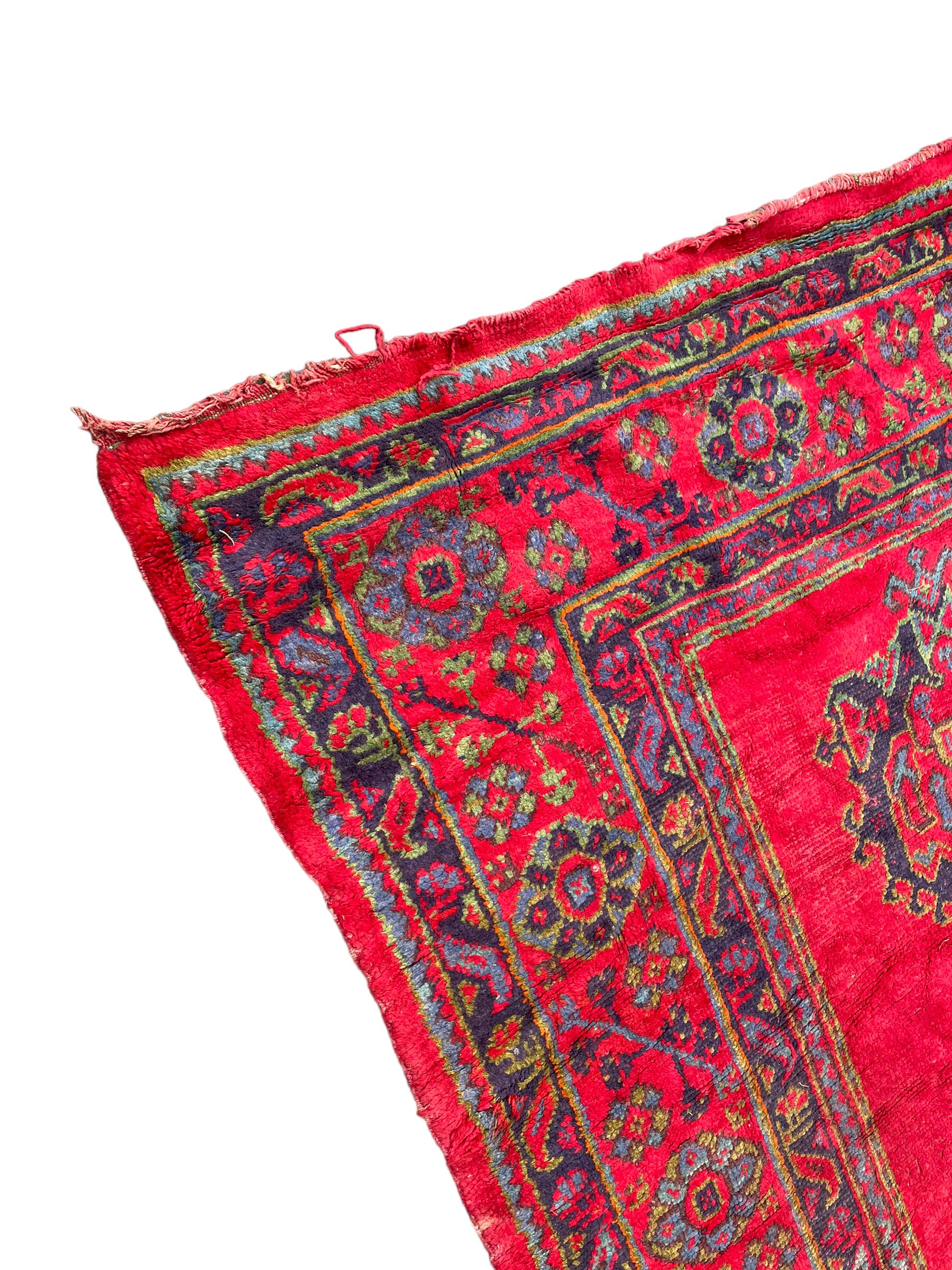 Early 20th century Western Anatolia Turkish Oushak crimson ground carpet, the field decorated with rows of Herati and Palmette medallions, the main border decorated with stylised flower head motifs within guard stripes