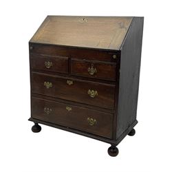 George III oak bureau, sloped fall-front enclosing a fitted interior with pigeonholes, small drawers, and a central compartment, over two short and two long drawers, brass escutcheons and drop handles, raised on bun feet