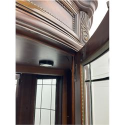  Kevin Charles American walnut demi lune display cabinet with illuminated interior, projecting cornice, two bevel edge glazed doors enclosing two adjustable shelves above single drawer and four cupboard doors with wine rack, carved scrolling supports