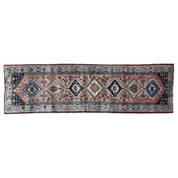 Persian Yalameh coral ground runner rug, the field decorated with seven hooked lozenge medallions surrounded by stylised plant motifs, the indigo spandrels decorated with similar patterns, guarded border with repeating diamond lozenges