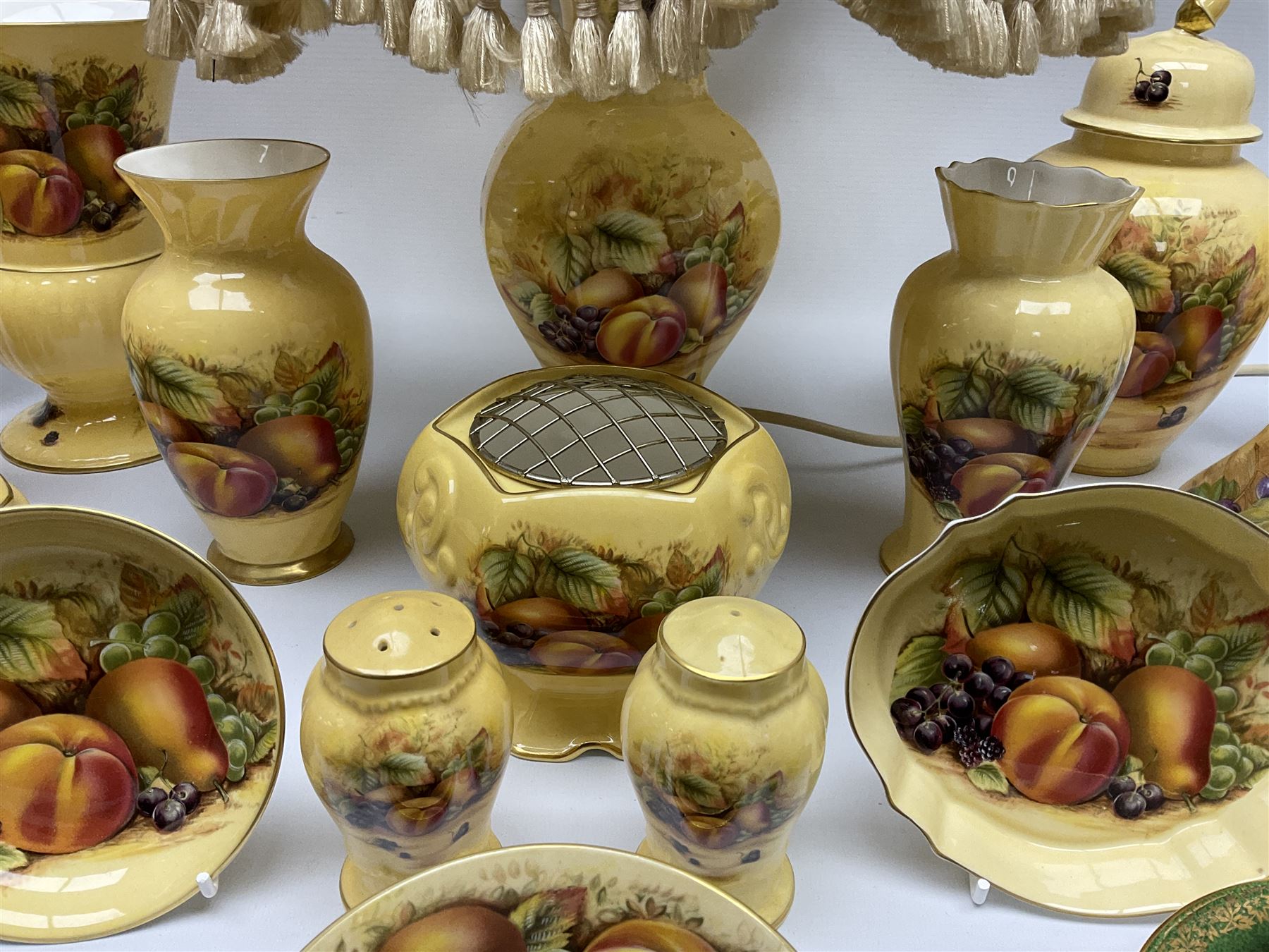 Collection of Aynsley Orchard Gold pattern wares, comprising lamp base, three jars and covers, six vases or various size and form, large jug, lidded dish, pair of cruets, pair of candlesticks, mug, two pin dishes, lobed dish, tea cup, saucer, size plate, and cake plate, and two further cups and saucers, each cup decorated with central Orchard Gold reserve to the interior against a mottled pink or green ground. 