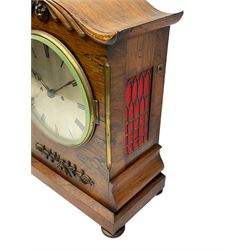A William IV c1820 twin fusee bracket clock in a rosewood case with a crested top and applied carving to the front, with a chamfered rectangular plinth raised on four bun feet, canted case corners with brass inlay, silk backed brass sound frets to the sides and a fully glazed door to the rear, with an 8” silvered circular dial, engraved Roman numerals, minute track and non-matching steel hands, cast brass bezel and flat bevelled glass, eight-day striking movement striking the hours on a bell. With Pendulum and pendulum lock. 