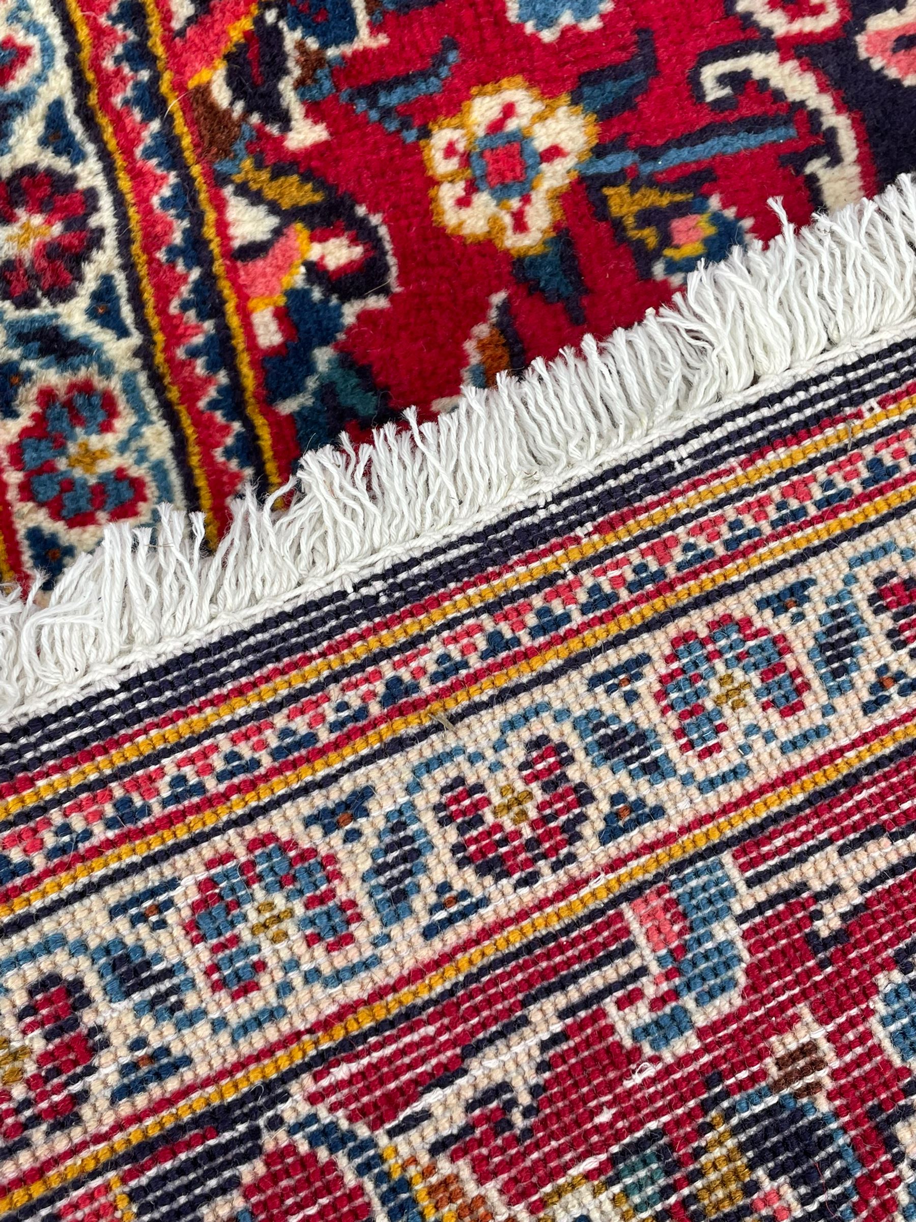 Persian indigo ground rug, the central crimson pole lozenge medallion surrounded by interlacing floral patterns, the main border with repeating plant motifs connected by scrolling branches