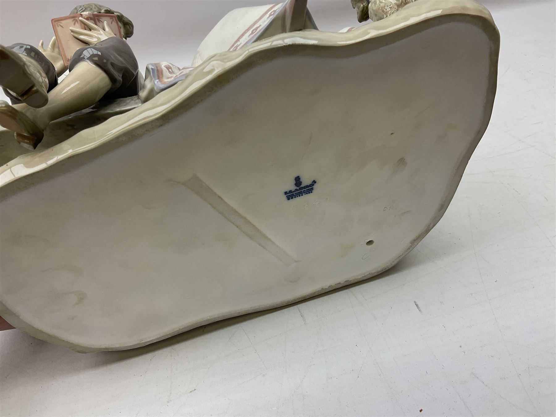 Lladro figure, Poetry of Love, modelled as a boy seated reading from a book next to a girl on garden bench with a dog at her feet, sculpted by Regino Torrijos, with original box, no 5442, year issued 1987, year retired 1998, H22cm