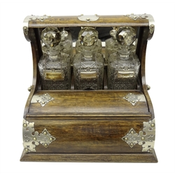  Early 20th century oak roll top tantalus, the three cut glass decanters with faceted stoppers and mirrored panel behind, silver-plated labels for 'Port', 'Brandy' and 'Sherry', silver-plated mounts with side carrying handles and lift-out interior containing cribbage board, W36cm, D28.5cm, H30.5cm  