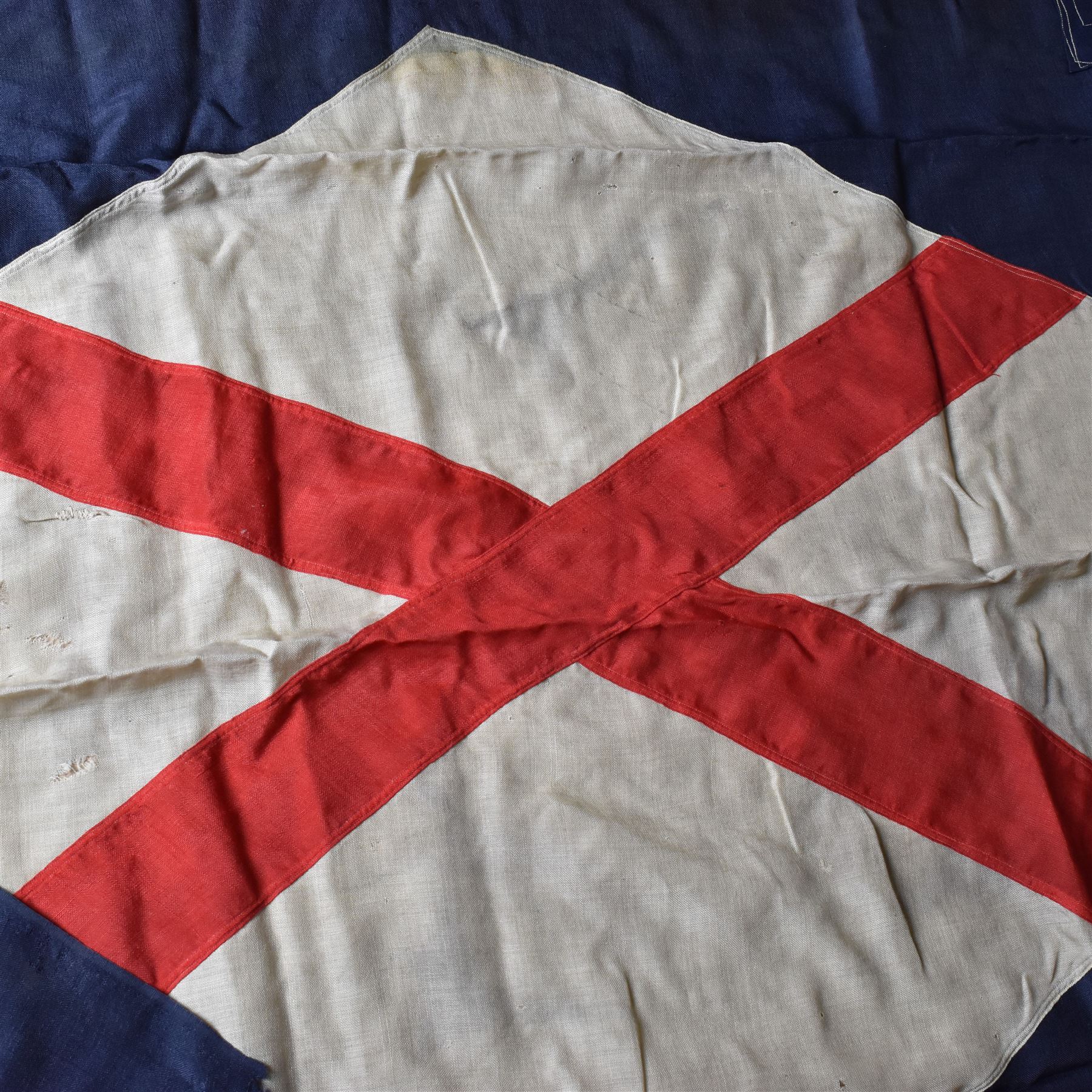 Ship's house flag, rectangular linen flag, with a white diamond and red cross to the centre, upon a cobalt blue ground, inscribed on the hoist 'Cutty Sark', H130cm, W170cm

Provenance by vendor repute: Vendor's father was a naval cadet in 1940s/50s on board HMS Worcester which was moored alongside the Cutty Sark on the River Thames at Greenhithe. He has had the flag since then. 