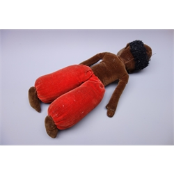  Norah Wellings style black doll, the pressed felt head with inset glass eyes and painted open mouth with teeth, brown velveteen body and red trousers H34cm  