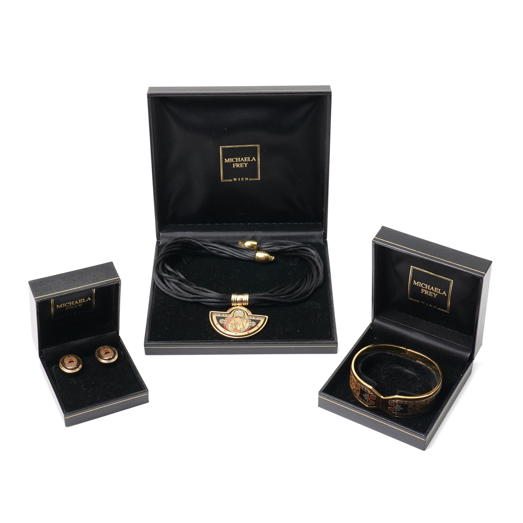 Michaela Frey gold plated and enamel suite of jewellery from the Greco-Roman collection, including a pair of oval stud earrings, hinged bangle and pendant on multistrand rope necklace, all boxed