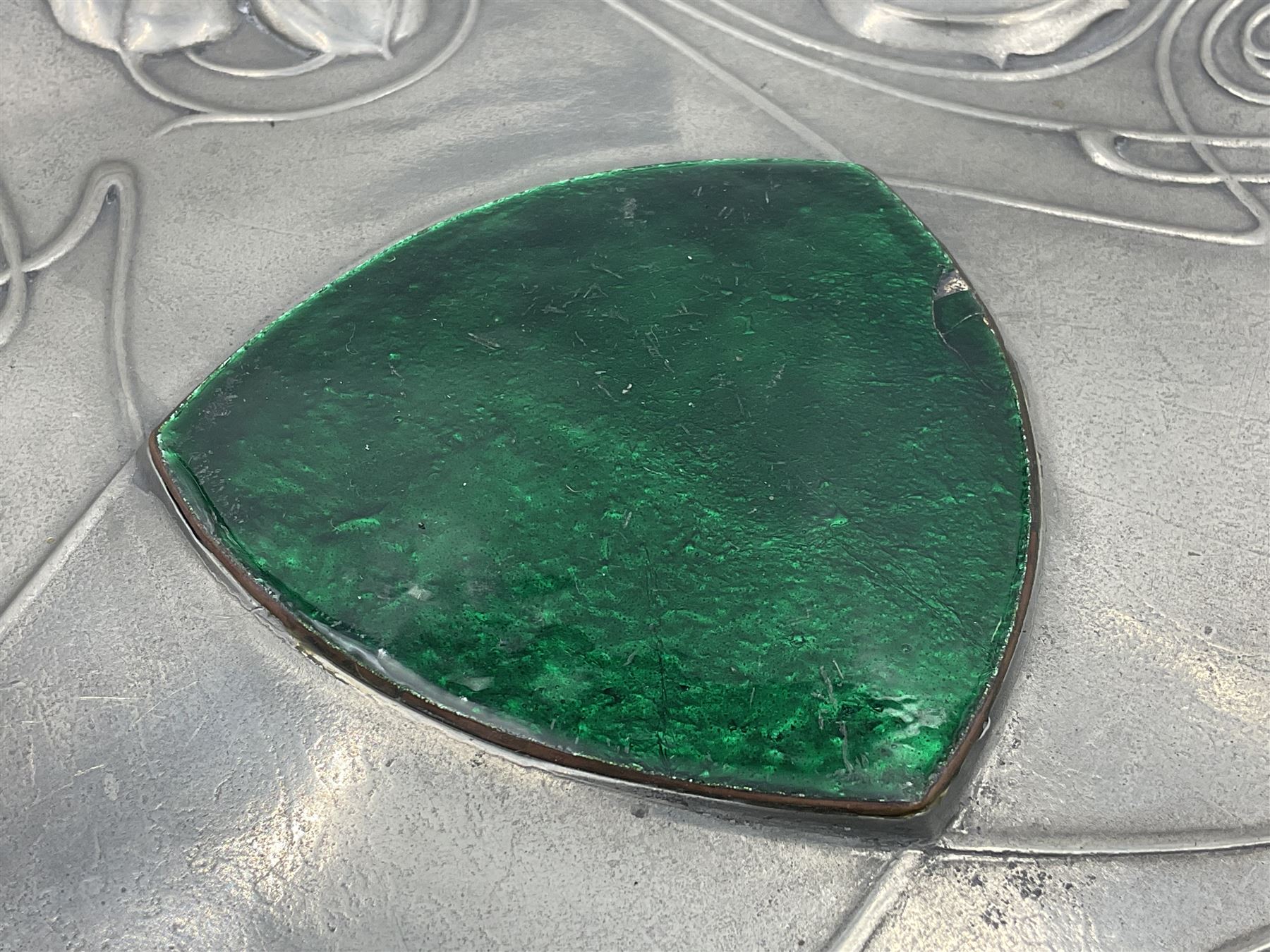 Liberty & Co Tudric pewter Bollelin tray, designed by Archibald Knox, of circular form with shaped edge, cast in relief with foliate tendrils surrounding a green enamel cartouche, impressed beneath Made by Library & Co English Pewter 044, D25.5cm