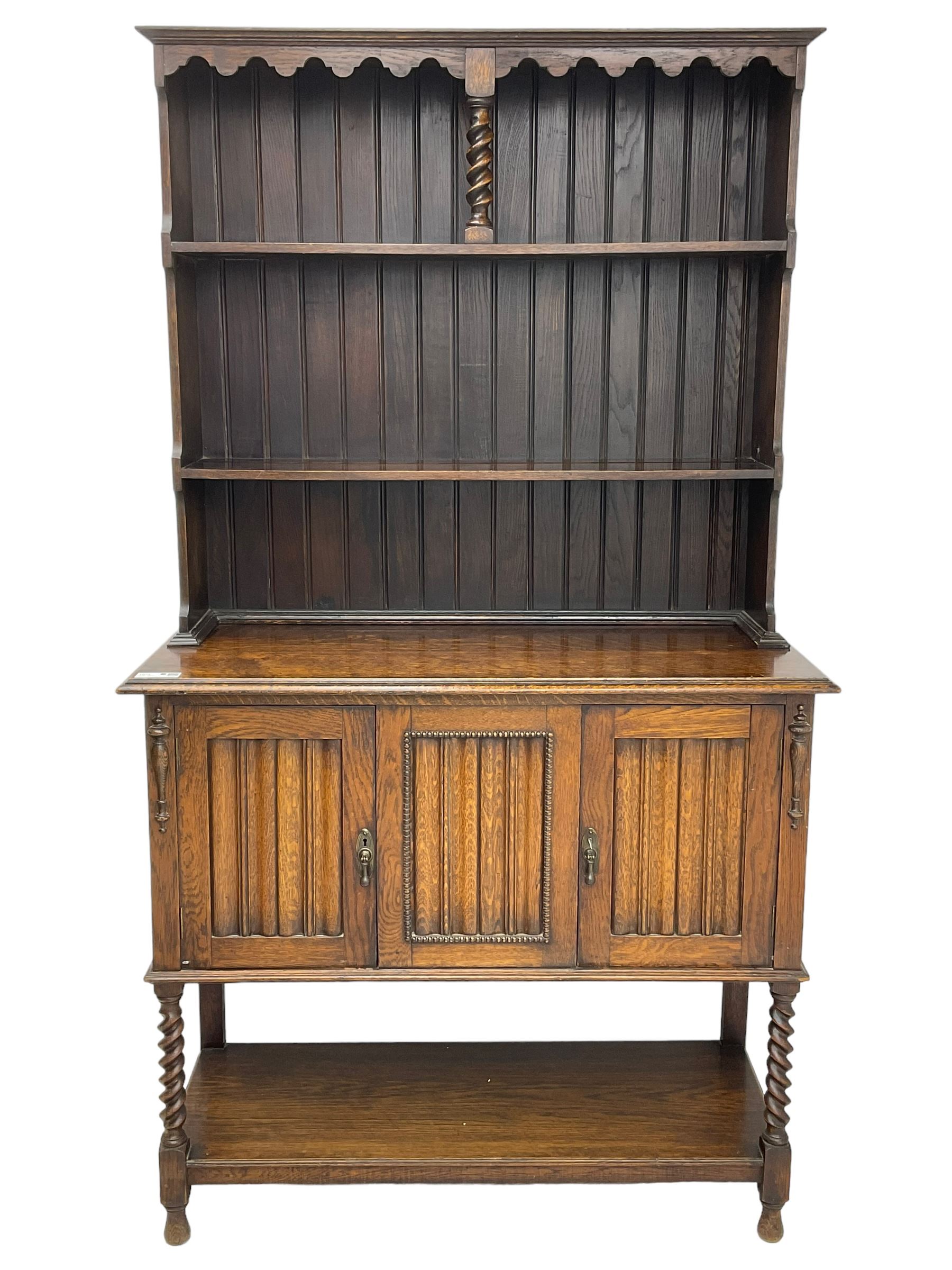 Early to mid-20th century oak dresser, raised two tier plate tack over two linenfold panelled doors, on spiral turned supports united by undertier 