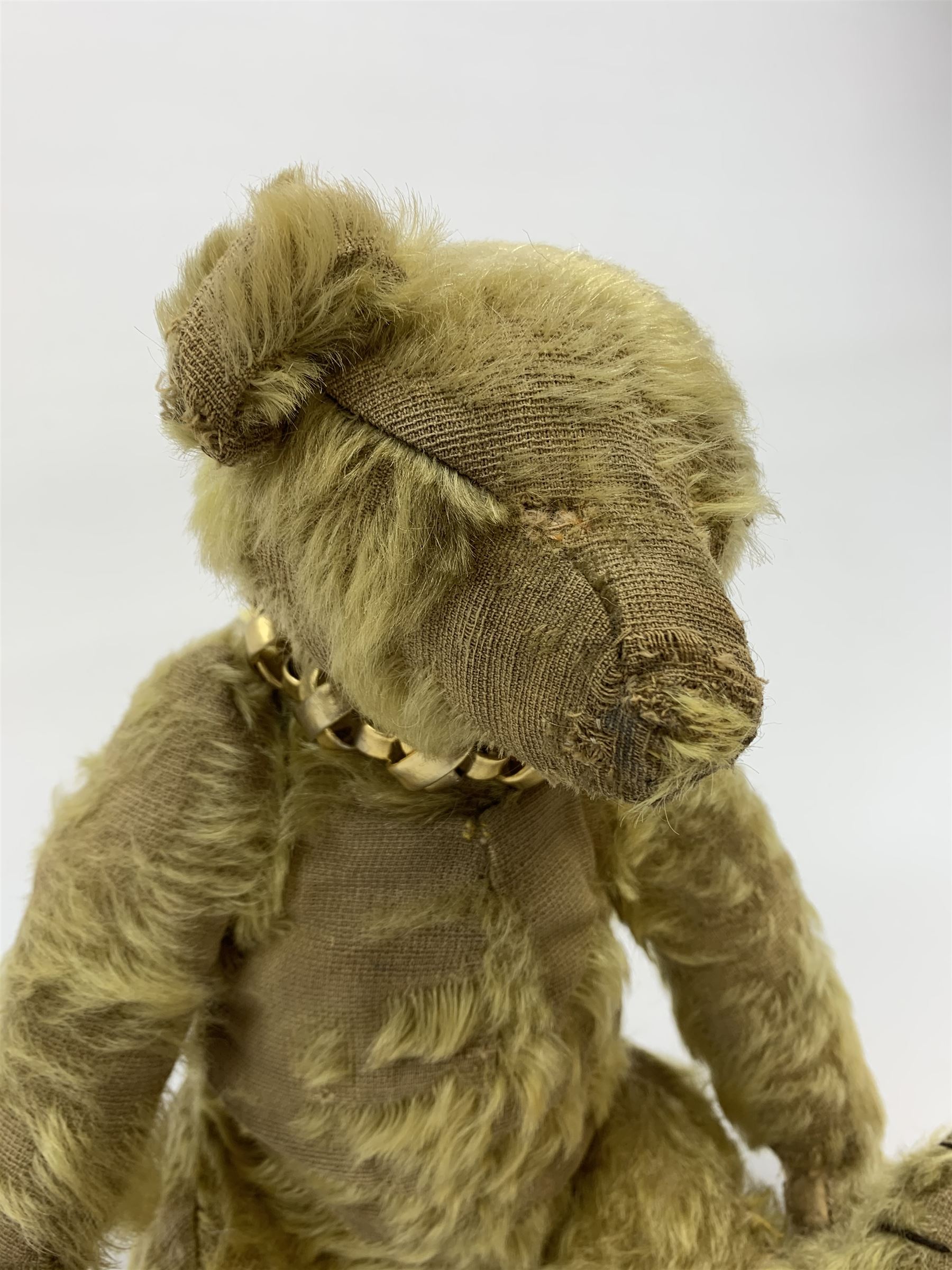 Early 20th century English teddy bear, with wood wool filled body with jointed limbs, felt covered paw pads, five claw stitching to feet and elongated arms with spoon shaped paws H14
