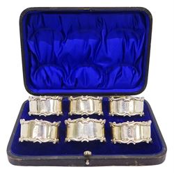 Set of six Edwardian silver napkin rings, of oval form with scroll detailed rims and engraved initials, hallmarked Harrison Brothers & Howson, Sheffield 1906, contained within a fitted case with blue silk and velvet lined interior, approximate silver weight 5.46 ozt (170 grams)