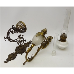  Cast brass wall mounting oil lamp, openwork cast bracket with milk glass oil lamp and chimney, H40cm and a similar continental wall oil lamp with ornate case bracket and glass reservoir   
