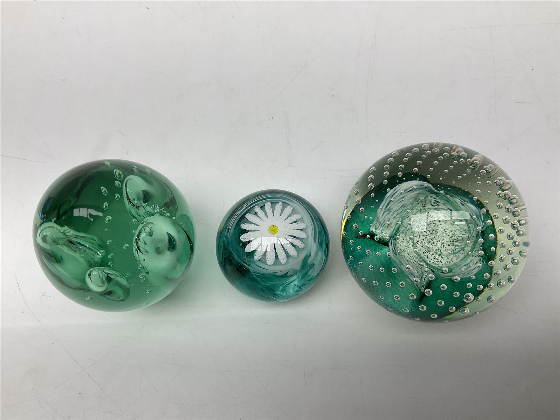 Three millefiori paperweights, together with a green glass dump paperweight with air bubble inclusions, Caithness Daisy and Cauldron paperweights and two small Caithness glass vases, tallest H9cm
