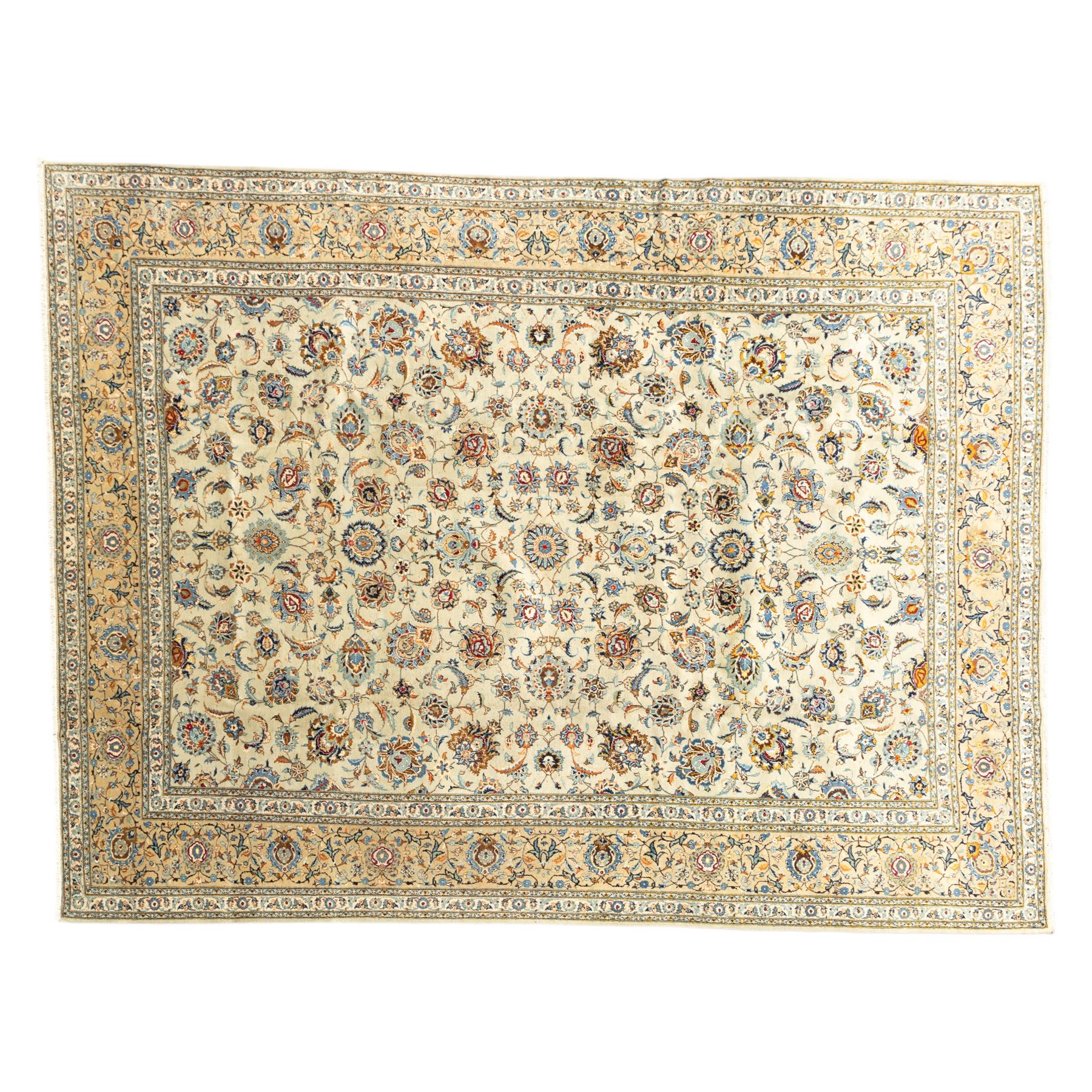 Central Persian Kashan hand-knotted carpet, cream ground with radiating floral rosette medallion in soft blue and terracotta, the field filled with stylised blooms, cloudband vines and palmette motifs, enclosed by triple borders featuring lotus and boteh designs, with cotton fringe ends 