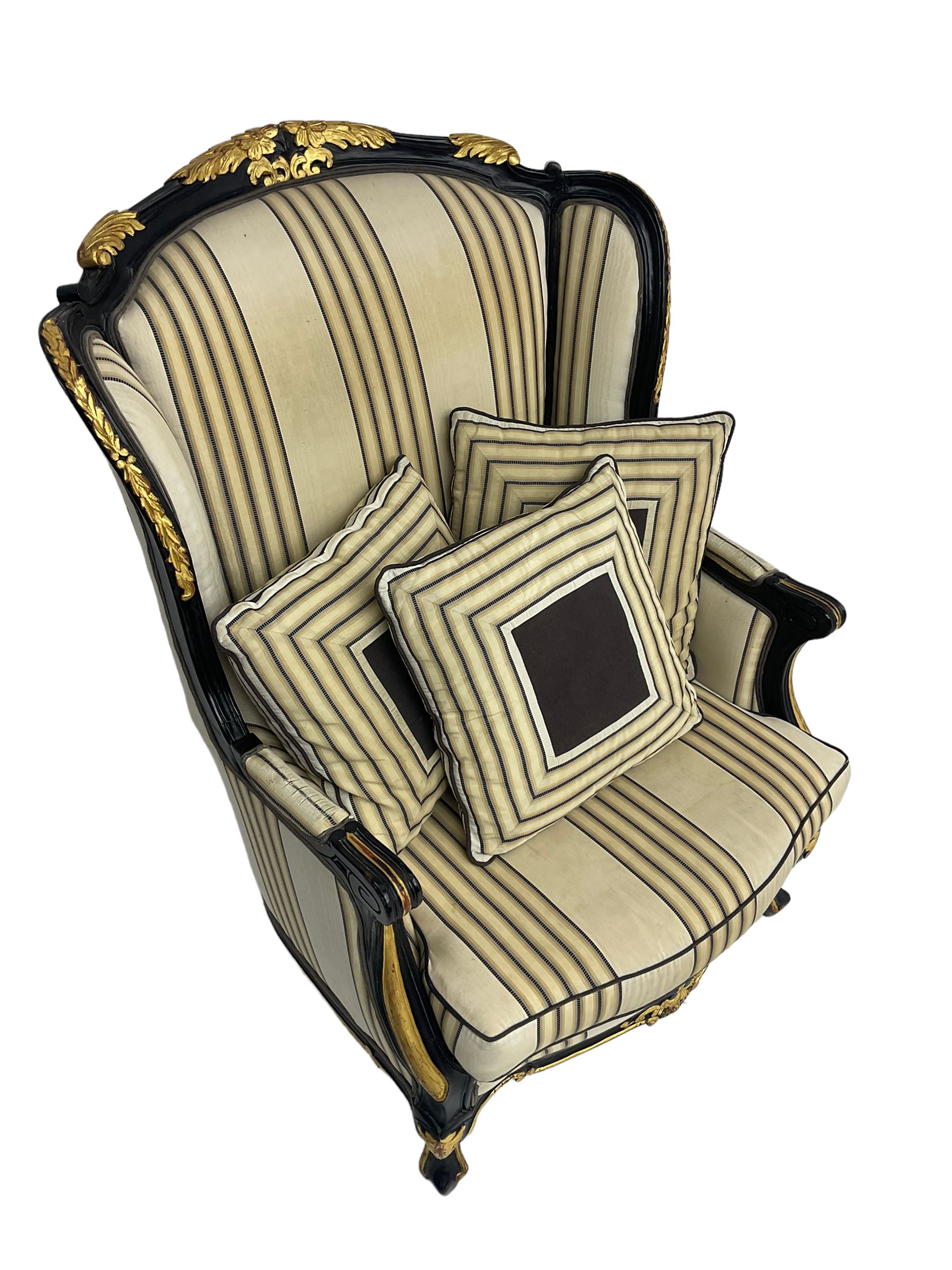 Thomas Messel - Georgian style ebonised and gilt wingback armchair, upholstered in striped fabric, on cabriole front feet