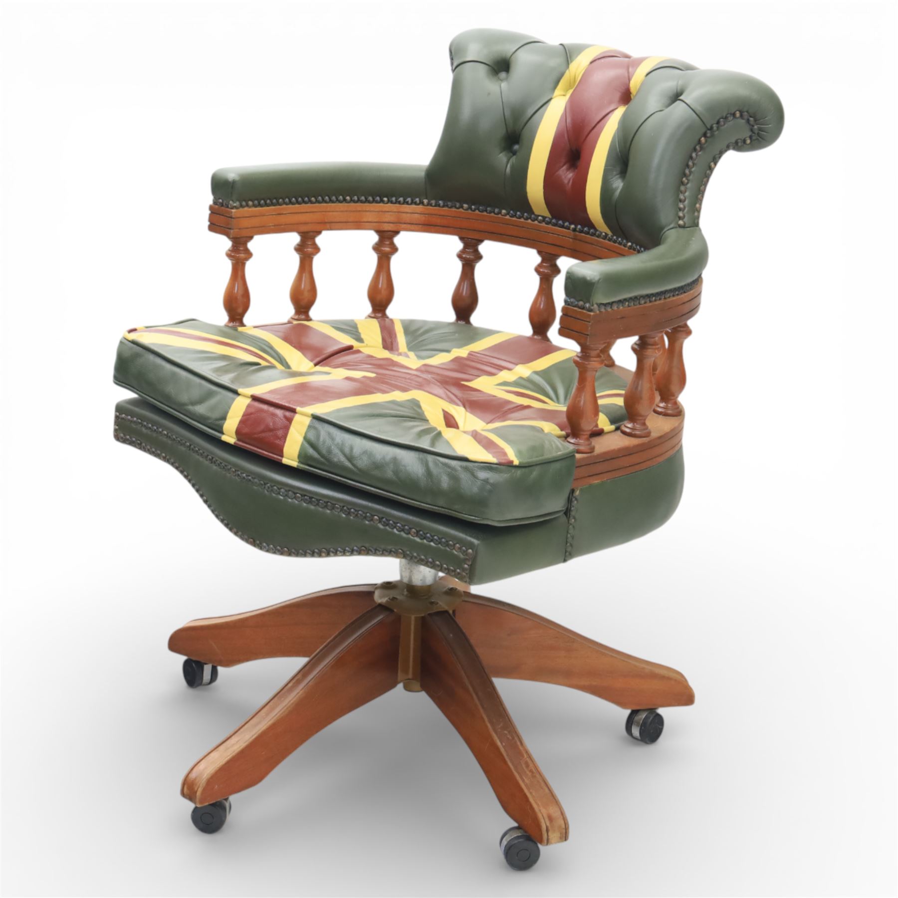 Late 20th century captain’s swivel desk chair, button upholstered back and seat in green leather with Union Jack motif panels, brass stud edging, curved padded arms with turned spindle supports, revolving and height adjustable action, on a five branch wooden base with castors