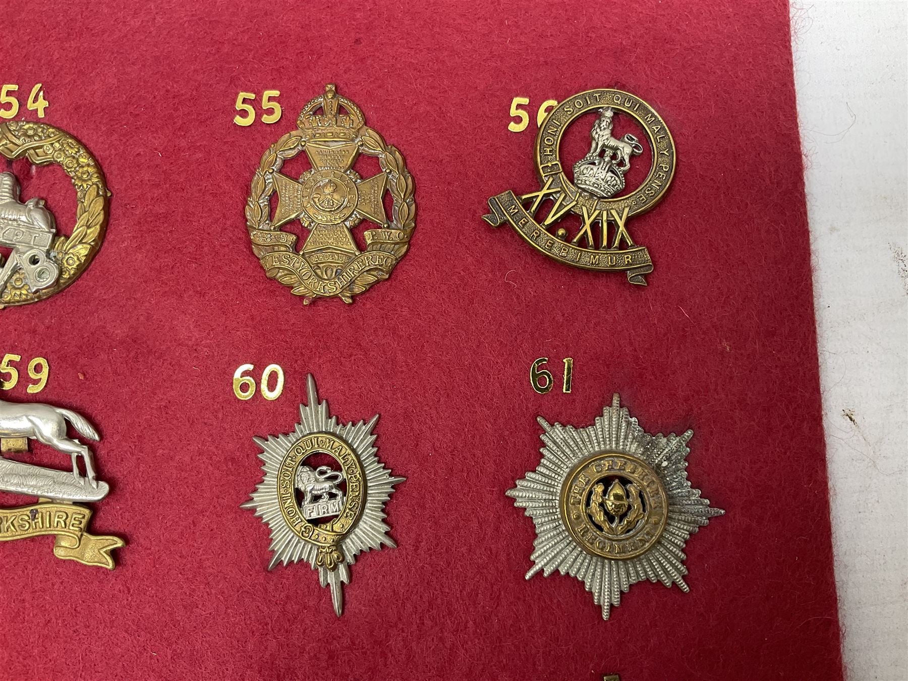 Twenty cap badges including Welsh Guards, Kings Royal Irish Hussars, York & Lancaster,  Loyal Suffolk Hussars, North Stafford, Durham Light Infantry, Cheshire, West Yorkshire, Norfolk, South Wales Borderers, Dorsetshire etc; mounted on a board for display