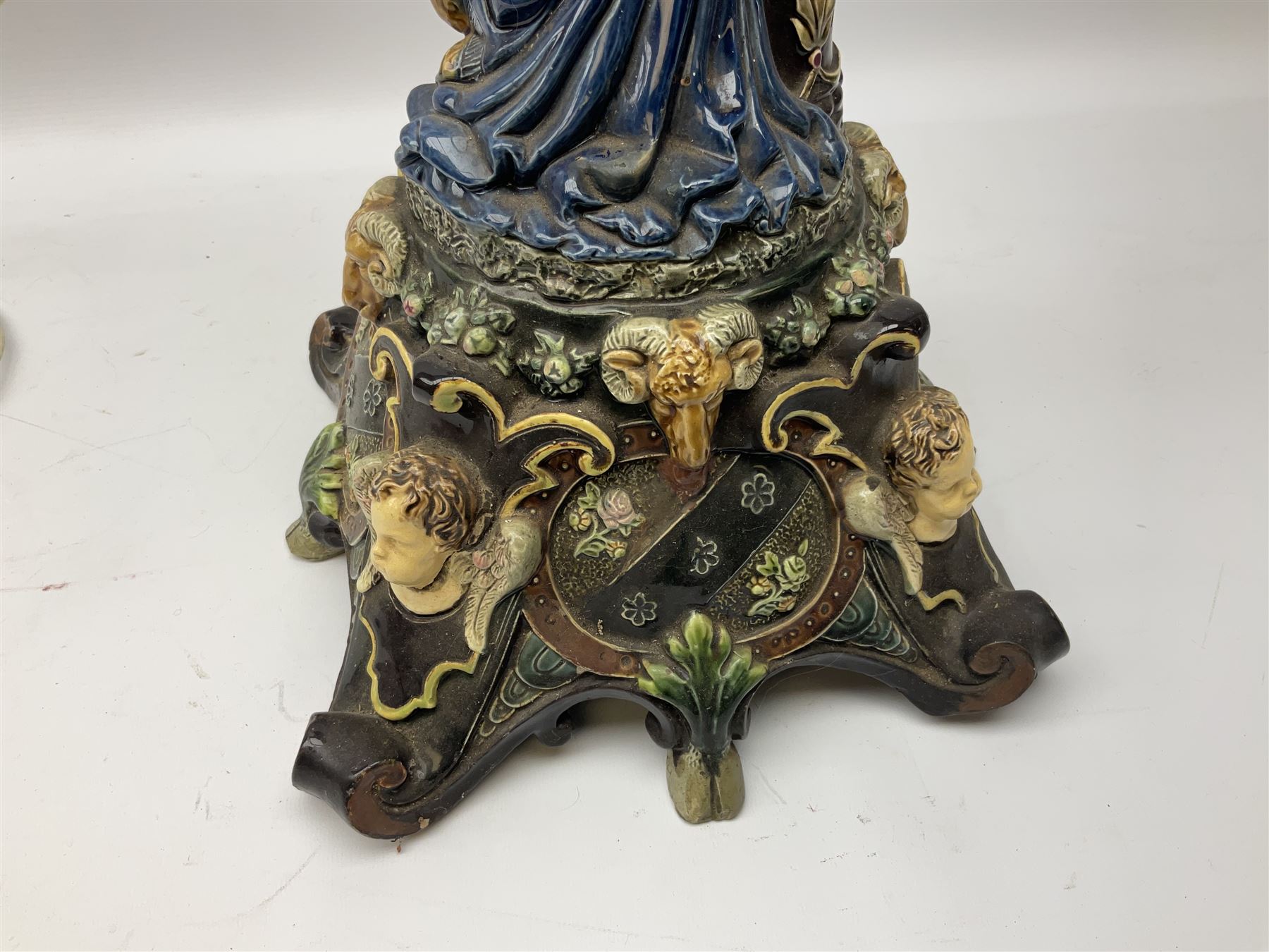 Composite table lamp modelled as a Roman Emperor donning blue robes, upon quatrefoil base modelled with rams heads and winged cherubs, H56cm excl fitting