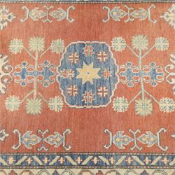 Persian Kazak vermillion ground rug, decorated with a foliate pole medallion with surrounding geometric and plant motifs, the guard bands with repeating floral and geometric design