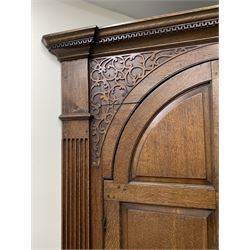 Large George III oak corner cupboard, projecting cornice over two stepped arch doors with fielded panels and blind fret work spandrels, flanked by fluted uprights, cupboard below enclosed by two fielded panel doors, the painted interior fitted with shaped shelves
 