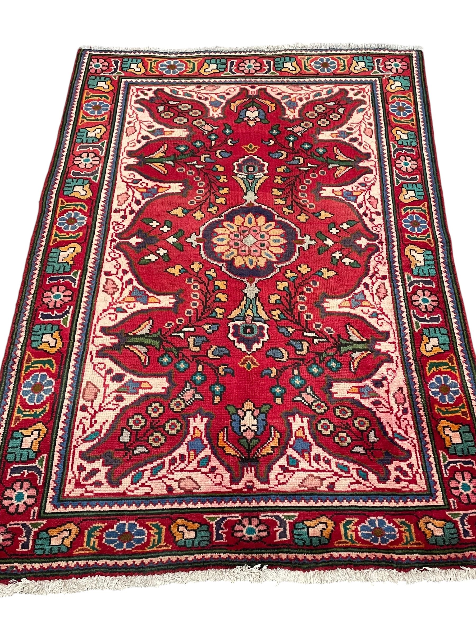 Persian Azerbaijan crimson ground rug, the field decorated with central floral motif and surrounded by trailing floral branches, enclosed within a shaped outer band with further floral decoration, the border with repeating flower heads, geometric guard stripes 