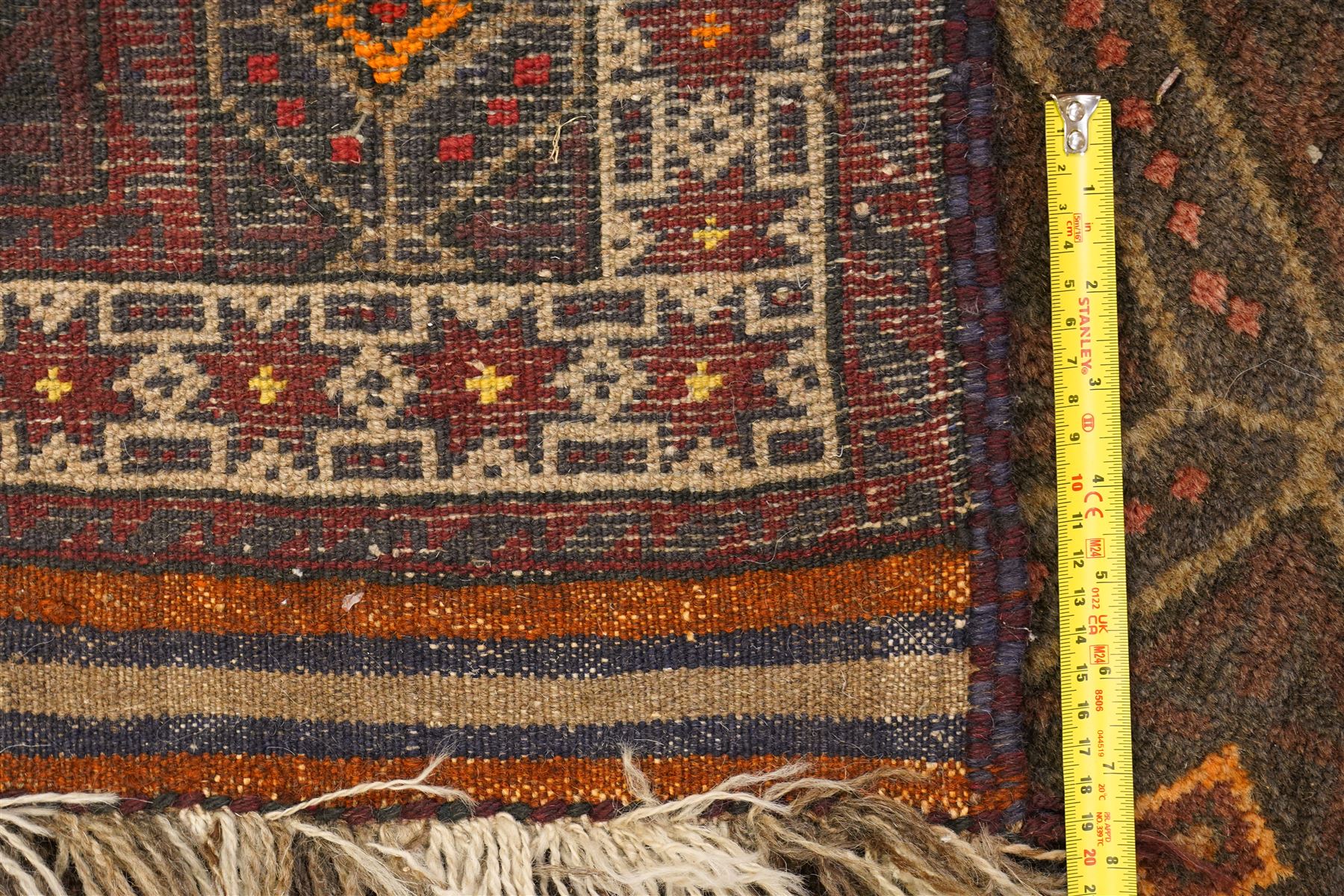 Two hand-knotted rugs, comprising Persian medallion rug and tribal rug, Persian hand-knotted rug, ivory ground centred by shaped floral medallion with pendants, surrounded by stylised flowerheads and foliate motifs, enclosed by multiple floral and geometric borders, H155cm, W123cm; tribal hand-knotted rug, dark brown ground with repeating linked geometric diamond medallions in orange and green, enclosed by ivory geometric border, striped ends with fringes, H150cm, W71cm
