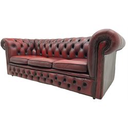 Chesterfield three seat sofa, upholstered in deep buttoned oxblood leather, on castors