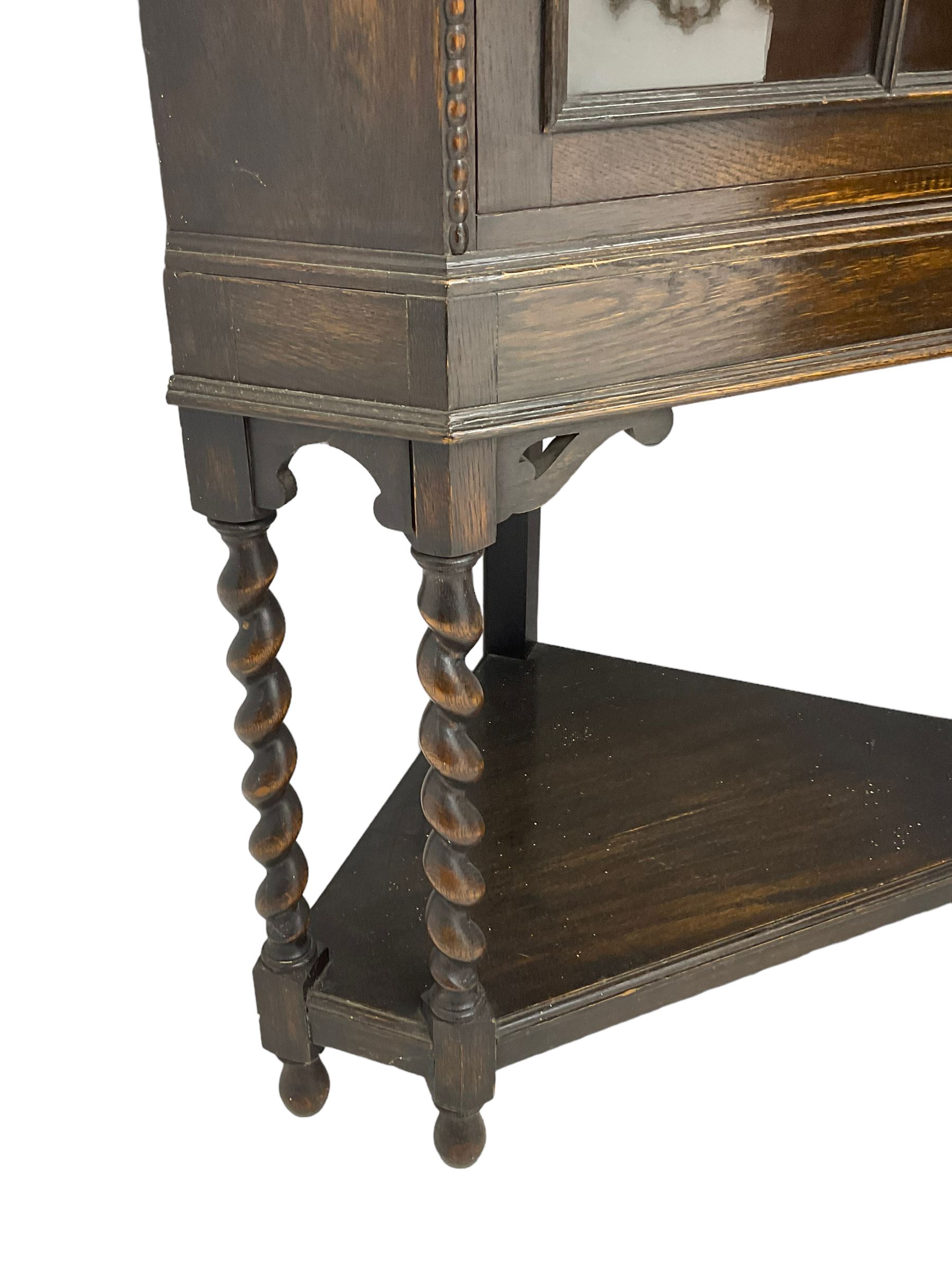 Early 20th century oak corner display cabinet, enclosed by glazed door, on spiral turned supports joined by undertier 