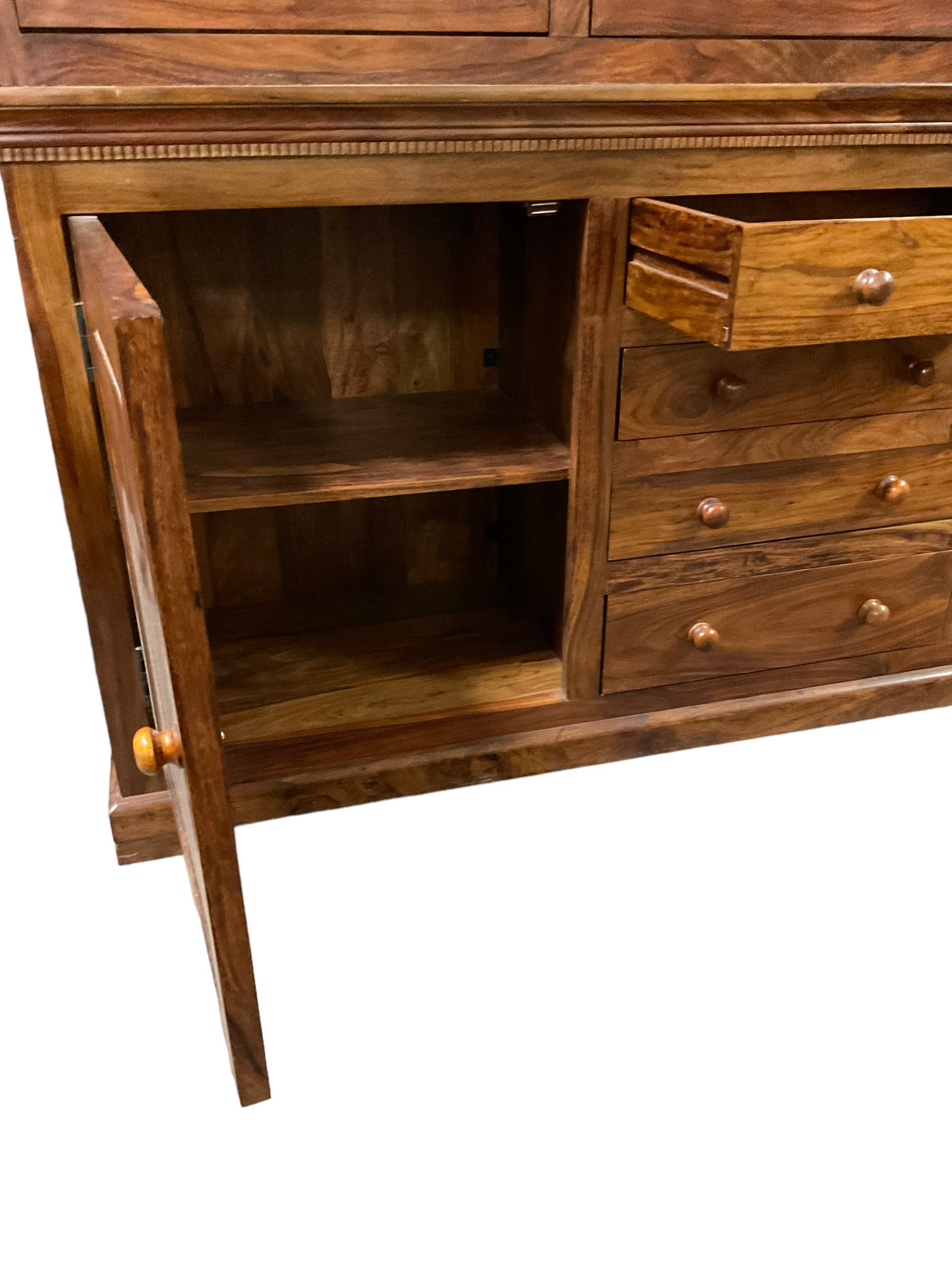 Large hardwood display wall unit, the upper section fitted with three glazed doors enclosing six shelves, the lower section fitted with four central drawers flanked by two panelled cupboards