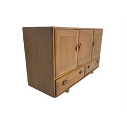 Ercol - light elm sideboard, fitted with three cupboards and two drawers, on castors