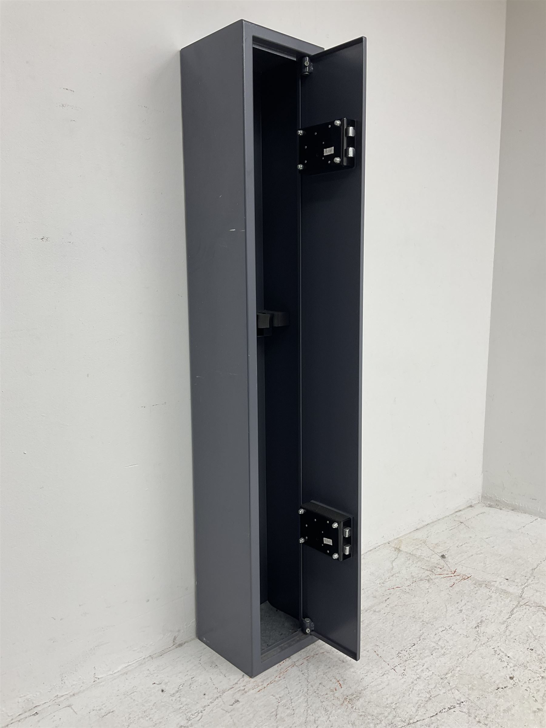 Grey steel wall mounting gun cabinet to accommodate three guns; single door with two locks with two keys for one lock; internally H128.5cm W21cm D17.5cm; externally H129cm W21.5cm D20cm
