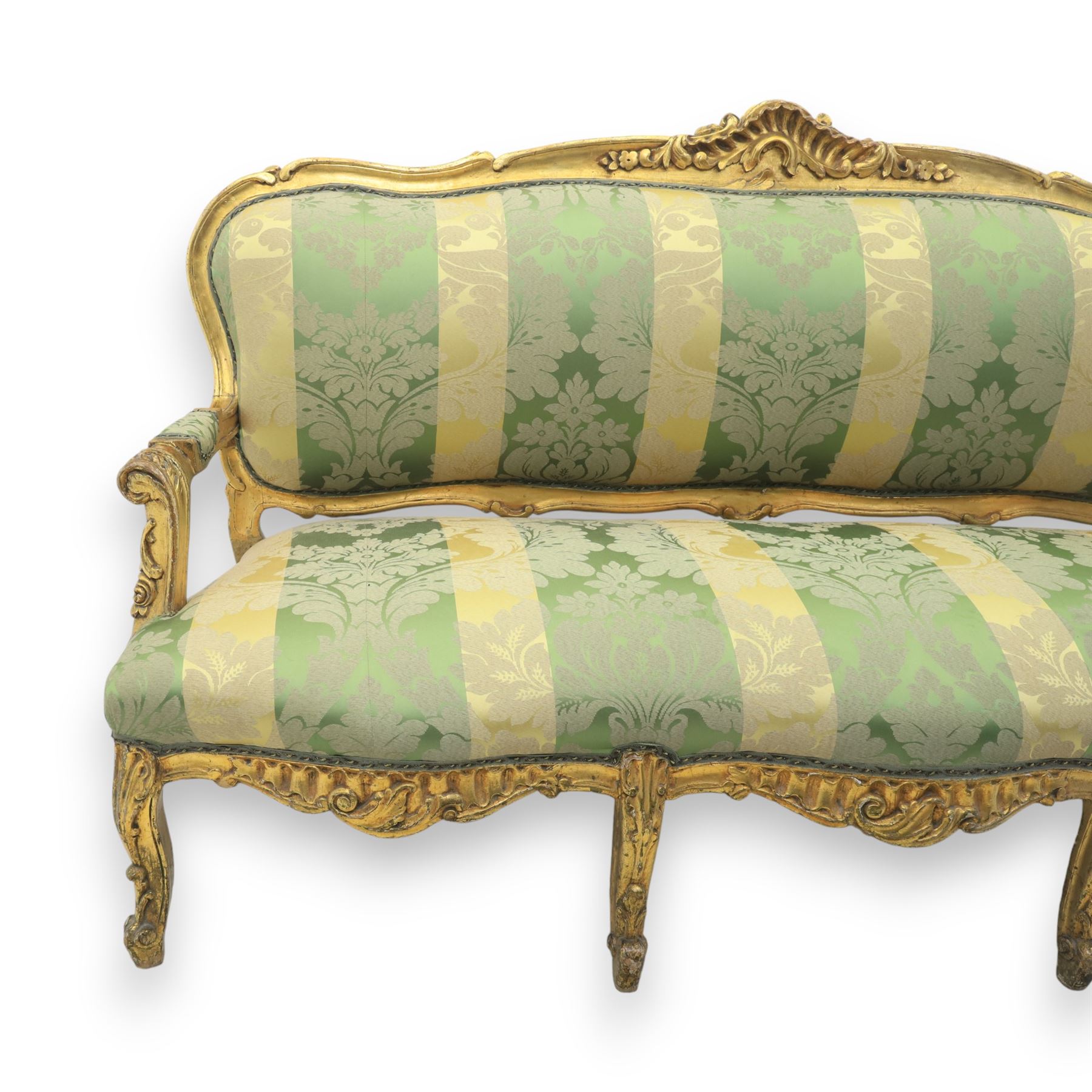 20th century French Louis XV style giltwood salon sofa, with shaped and moulded serpentine cresting rail carved with central scroll motif, padded back and seat upholstered in green and gold striped damask fabric, scroll carved open arms with padded rests, shaped apron carved with rocaille and foliate motifs, raised upon cabriole legs