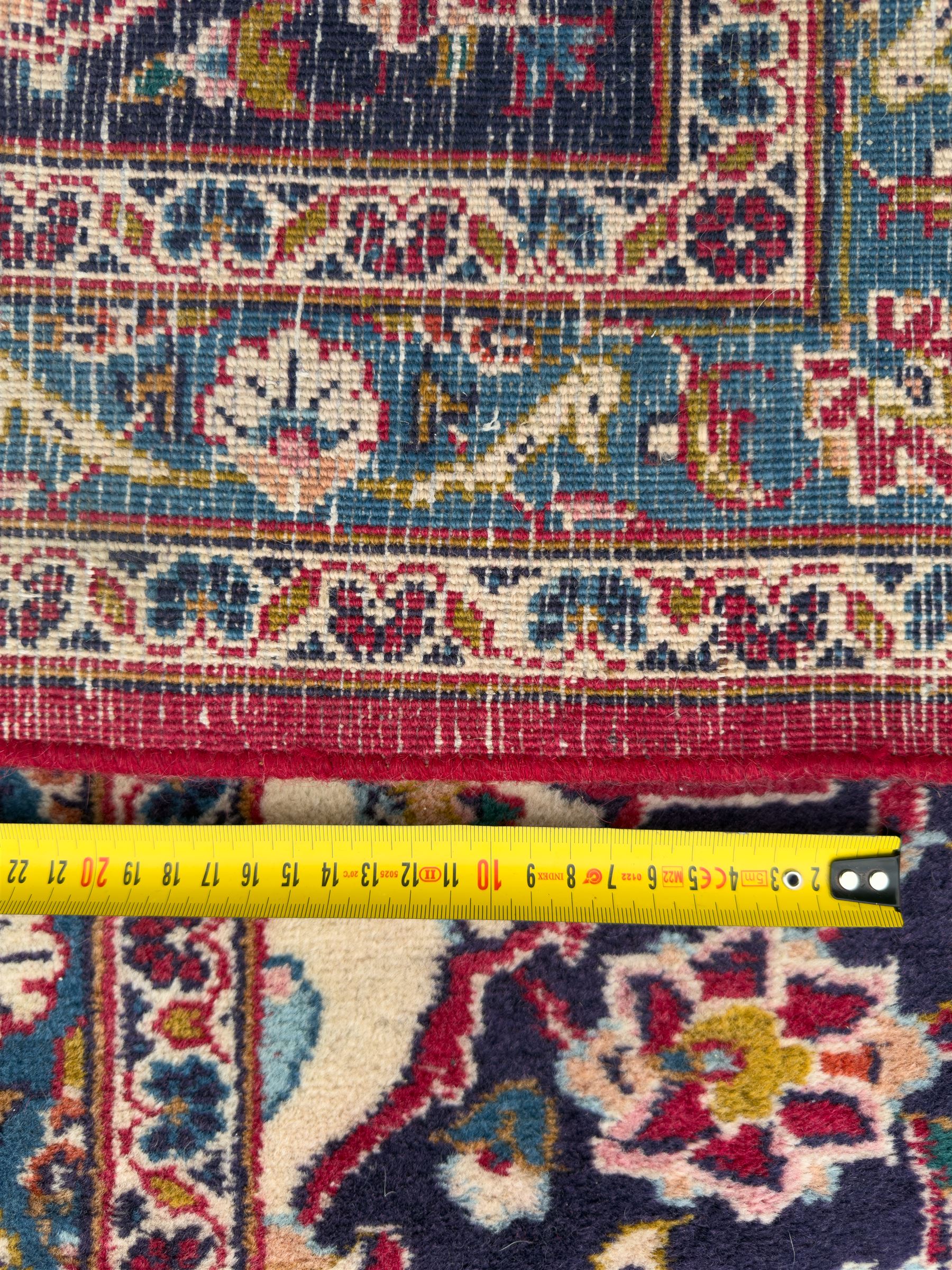 Pair of Persian wool rugs, each with rich red ground, one centred with a diamond-shaped medallion and navy spandrels within a floral field, the other with radiating floral medallion and scrolling foliate motifs, both enclosed by multiple borders with palmette and flowerhead designs, from the region of Kashan 291x376, 299 x 378 