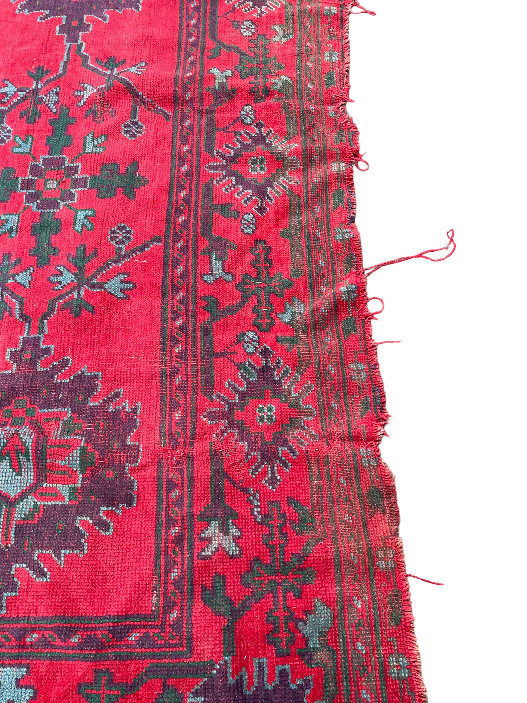 Early 20th century Western Anatolia Turkish Oushak crimson ground carpet, decorated with large Palmettes with trailing branches, the main border decorated with repeating stylised motifs within guard stripes 