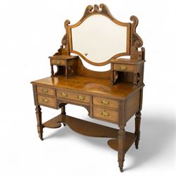 Late Victorian burr walnut veneer dressing table, the arched swing mirror surmounted by pierced scroll cresting, flanked by twin drawers on turned columns, over moulded rectangular top with five drawer arrangement, on block supports with shaped undertier