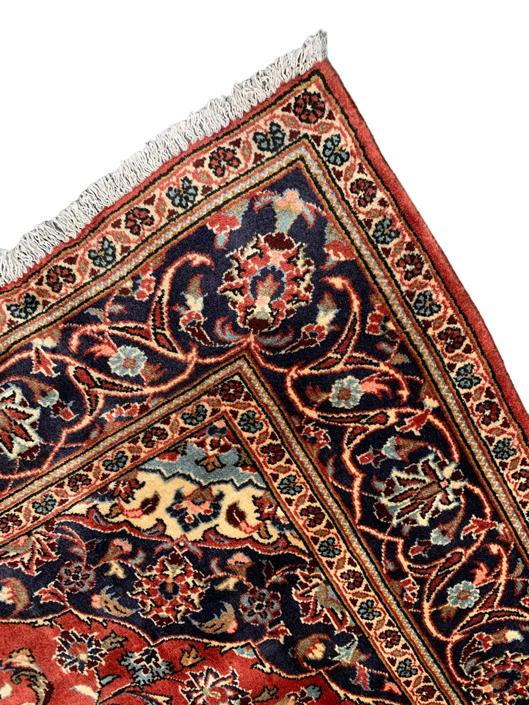 Persian Ardakan crimson ground rug, the field with shaped floral design medallion surrounded by curled leafy branches, scrolling border with stylised plant motifs