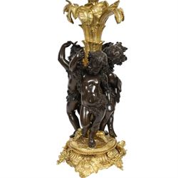 Louis XVI style gilt table lamp, the central column decorated with acanthus leaves, surrounded with three putti with vine leaf crowns, upon a circular base adorned with grape and vines, with shade, H64cm
