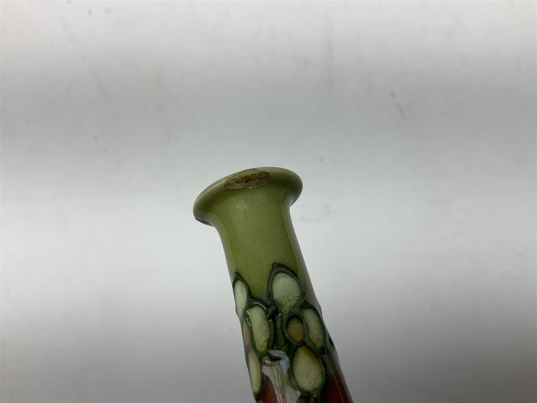 Three Minton Secessionist vases, with tube-lined stylised flower decoration, two upon a red ground and third upon a purple ground, all with printed mark to base 'Minton Ltd, No. 33', H13cm