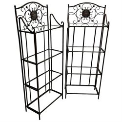 Pair of wrought metal conservatory plant stands, raised back with scrolling design, each fitted with three glass shelves