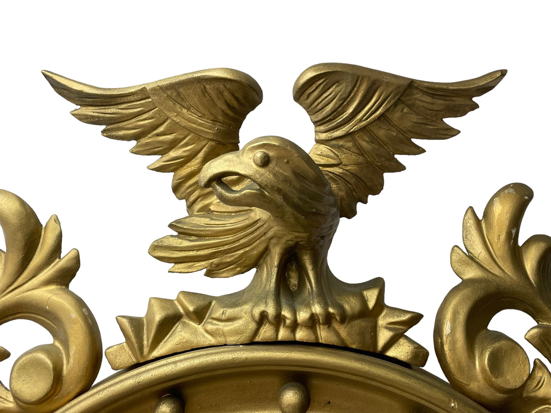 Pair of Regency period giltwood convex wall mirrors, moulded circular frame decorated with spherical mounts surmounted by a carved eagle with spread wings, foliage scroll carved upper and lower brackets, reed moulded and ebonised slip enclosed convex mirror plate 