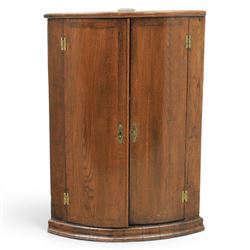 George III oak cylindrical corner cupboard, bow fronted doors revealing a painted shelved ...